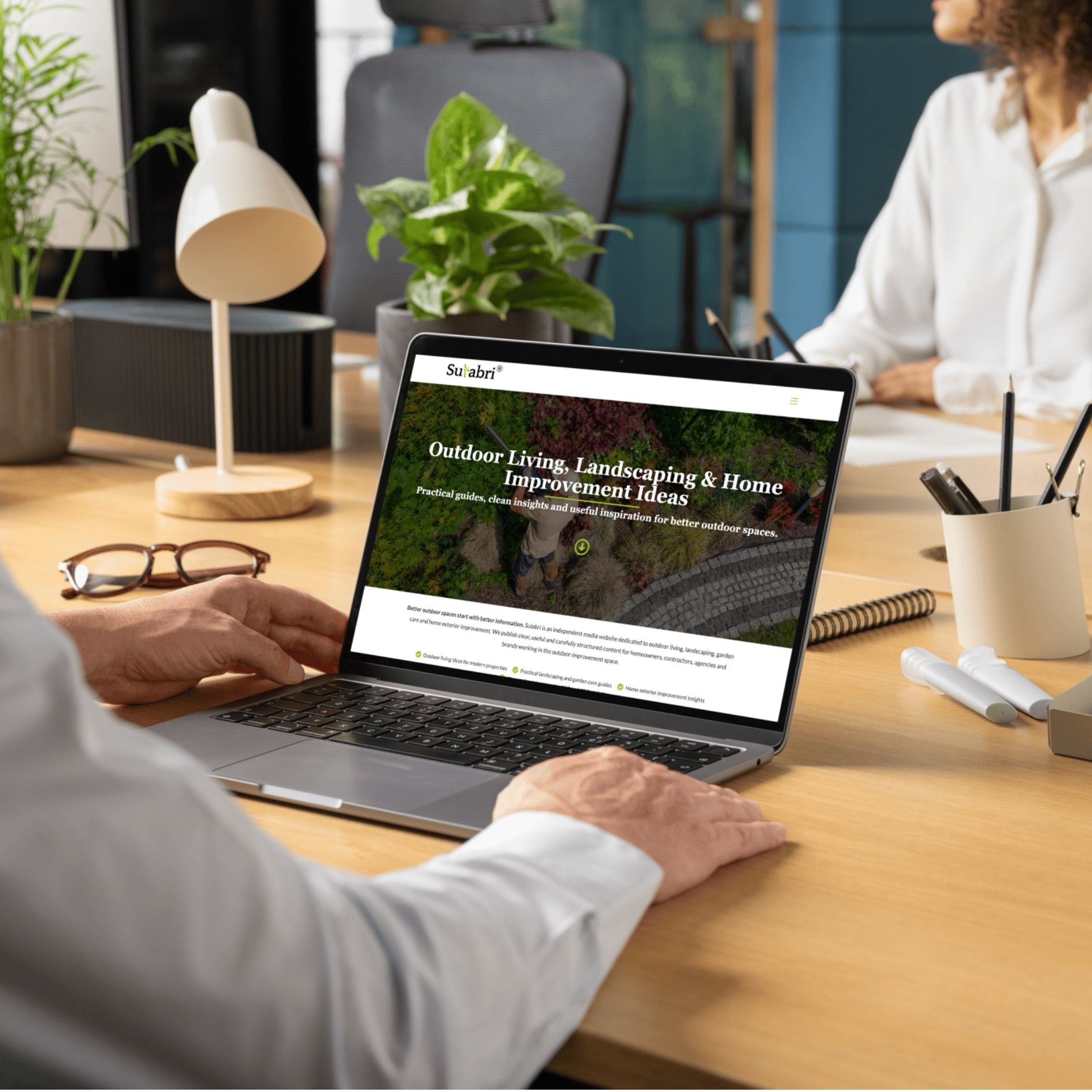 Un ordinateur portable affichant le site sulabri.com sur un bureau en bois, avec des plantes et des accessoires de bureau.